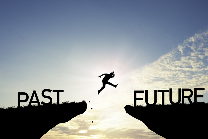 Photo of a man straddling a past and future sign